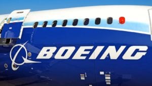 Boeing (BA) passenger airplane with open exit door, passenger windows, cargo door, close up view of Boeing logo