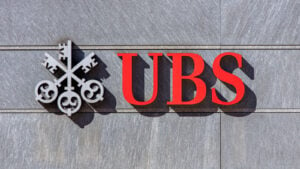 UBS (UBS) bank sign on gray stone wall with red and gray logo