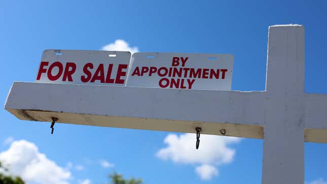 A white For Sale signpost in front of a blue sky.