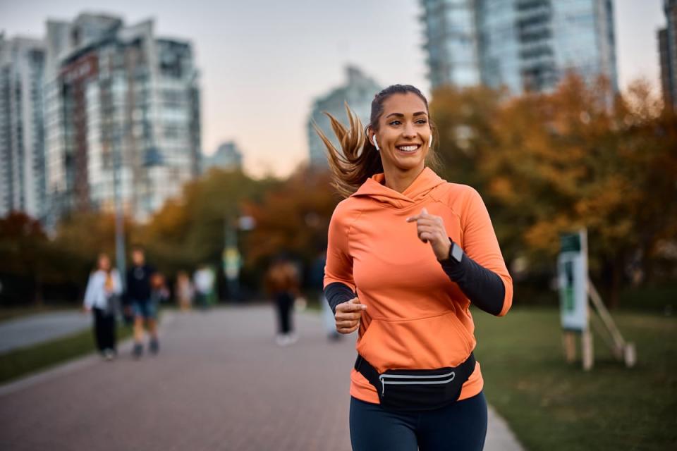 A person smiling while running with wireless ear buds. 