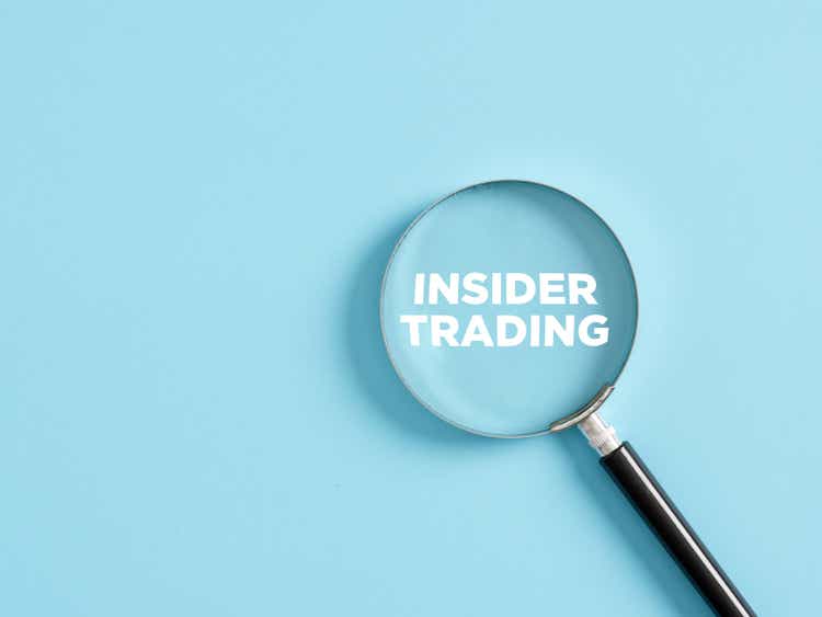 Magnifier with the text insider trading on blue background.