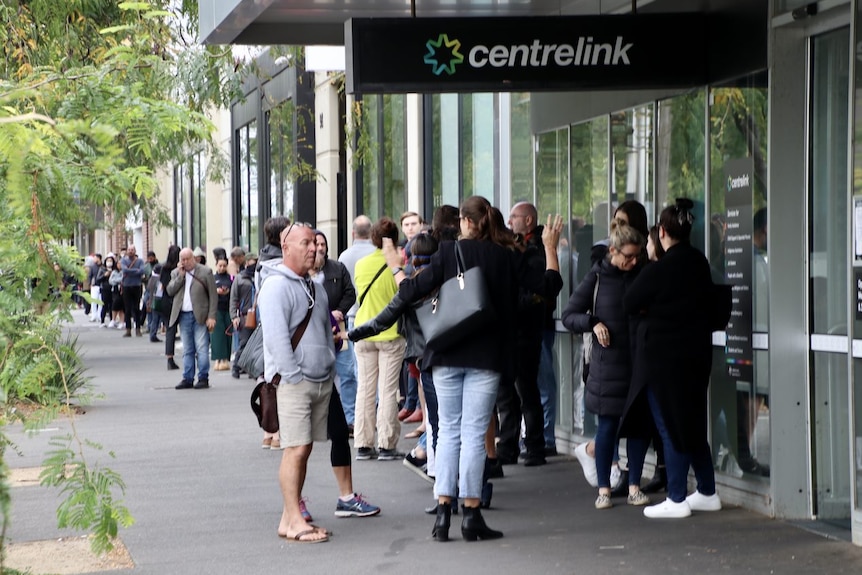 A queue of people stretches down York Street in South Melbourne, starting at the entrance to a Centrelink building.